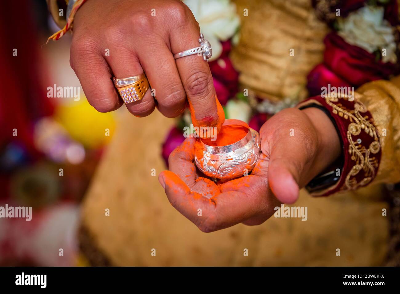 The Groom's hand holding sindur or Vermilion before applying on the bride`s hair-parting. Stock Photo